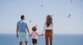 Back view of family on the beach on sky. People having fun on summer vacation. Father, mother and child holding hands Royalty Free Stock Photo