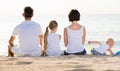 Back view on family of four sitting on beach . Royalty Free Stock Photo