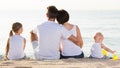 Back view on family of four sitting on beach Royalty Free Stock Photo