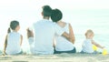 Back view on family of four sitting on beach Royalty Free Stock Photo
