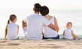 back view on family of four sitting on beach . Royalty Free Stock Photo