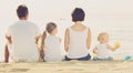 Back view on family of four sitting on beach Royalty Free Stock Photo