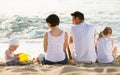 Back view on family of four sitting on beach Royalty Free Stock Photo