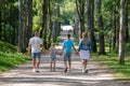 The back view of a family on a serene walk a father swings the youngest high as her siblings hold hands beside, a