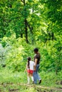 Back view of family walking in park forest around trees, talking, having fun. Summer activities, travelling. Vertical. Royalty Free Stock Photo