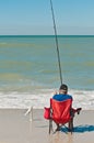 Senior male siting n beach chair surf fishing