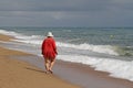 Back view of a fat woman walking alone on a sunny day on the beach of the Mediterranean Sea