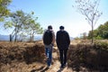 back view father and adult son with backpack walking to see scenic mountains in countryside Royalty Free Stock Photo