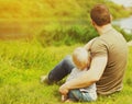 Back view father and son resting sitting together looking away on green grass summer near river Royalty Free Stock Photo