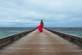 Back view of a female in a beautiful pink dress walking on a pier Royalty Free Stock Photo