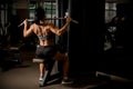 Back view of female bodybuilder pulled on sports simulator. Back muscles are very tense.