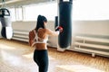 Back view of female boxer hitting a huge punching bag at fitness gym Royalty Free Stock Photo