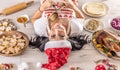 Back view of a female cook in a Christmas apron and Santa hat lying on the ground surrounded by gingerbread, Linz cakes, from the