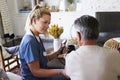 Back view of female healthcare worker measuring the blood pressure of senior man during a home visit Royalty Free Stock Photo