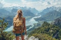 Back view of a female hiker with a backpack gazing at a stunning alpine lake surrounded by dramatic mountain peaks