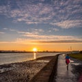 Back view of a female running on the coast of Dublin harbor at sunset