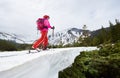 Back view of female skier on ski touring among snowy slope with backpack. Copy space on grey sky. Low angle snapshot Royalty Free Stock Photo