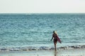 back view of female surfer with surfboard walking on beach into Royalty Free Stock Photo