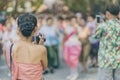 Back view of female in Thai dress take a photo of a Thai dance parade in Songkran festival