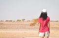 Back view female tourist stand curios watch camel in distance in desert on deserted landscape of Jordan countryside Royalty Free Stock Photo