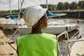 Back view female worker wearing hardhat in yacht docks