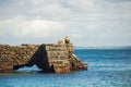 Back view of fisherman man sitting on the breakwater of Porto da Barra beach