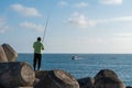 Back view of a fisherman on a shore and the fishing boat on the horizon in Peniche, Portugal