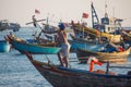 back view of fisherman standing on boat and other vessels floating behind, Vietnam,