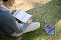 Back view, Focused young Asian male college student reading a book, relaxing in the campus park Royalty Free Stock Photo