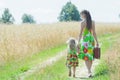 Back view full length portrait of walking mother and her little daughter on rural country road Royalty Free Stock Photo