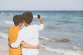 Back view gay portrait young couple smiling taking a selfie photo together with smart mobile phone Royalty Free Stock Photo