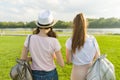 Back view, girl friends are walking in the park in nature. Girls walk along the green lawn, talk, have fun. Royalty Free Stock Photo