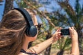 Back view on the girl in the headphones listening music  walks in the palm forest. Seychelles islands. Royalty Free Stock Photo