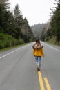 back view of girl hitchhiker in winter coat walking on road, adventure