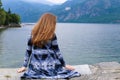 Back view of girl sitting near lake Como, mountain in background. Royalty Free Stock Photo