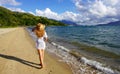 Back view of a girl in a straw hat and sundress walking barefoot on the sand on a beautiful deserted tropical beach Royalty Free Stock Photo
