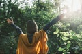 Back view. Girl wear long-sleeved shirt and wool hat while standing turning back In the midst nature and sunlight winter