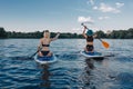 back view of girls surfing on paddle boards