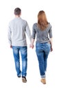 Back view going couple. walking friendly girl and guy holding h