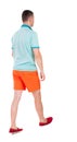 Back view of going handsome man in shorts. walking young guy