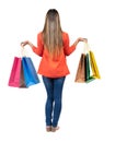 Back view of going woman in jeans woman with shopping bags . Royalty Free Stock Photo