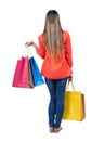 Back view of going woman in jeans woman with shopping bags . Royalty Free Stock Photo