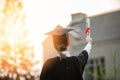 Back of view Graduate put hands up and celebrating with certificate in her hand and so proud Royalty Free Stock Photo