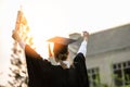 Back of view Graduate put hands up and celebrating with certificate in her hand and so proud and happiness in Commencement day