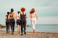 Back view of group of Caucasian women wearing sportswear jogging on beach. Ocean in background. Concept of outdoor sport