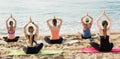 Females training various yoga positions on beach