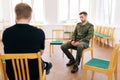 Back view of group male veterans in camouflage uniform talking sitting in circle during PTSD group therapy session