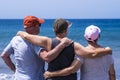 Back view of group of three friends senior people enjoying together the beach looking at the horizon over water - concept of Royalty Free Stock Photo