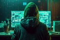 Back view of hacker in a hood with hidden face looks at the monitor screen with glowing code. Hacking and malware concept.