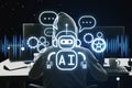 Back view of hacker using computers at desk with glowing robot ai hologram on dark background. Automated machine learning, hacking Royalty Free Stock Photo